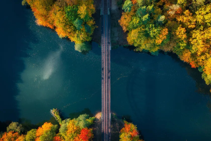 Overhead view of a railway bridge over a river surrounded by autumn foliage